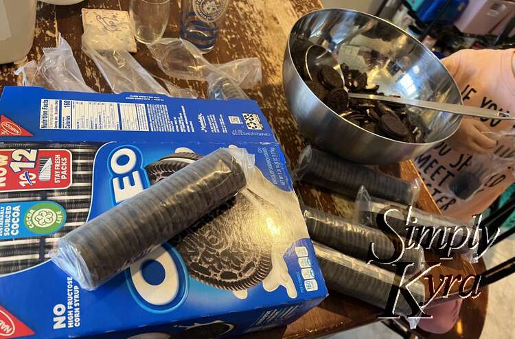 A Costco sized box of Oreo cookies getting crushed in a metal bowl. 