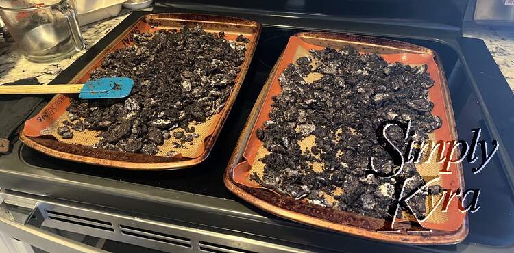 The mixed and crushed Oreo cookies laid out on two Silpat lined baking sheets. 