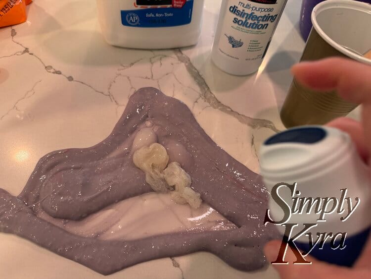 Spraying clear gel onto the stretched out purple slime.