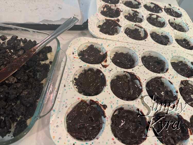 There are two white speckled silicon cupcake trays next to a square glass casserole dish. All have glistening black insides. 