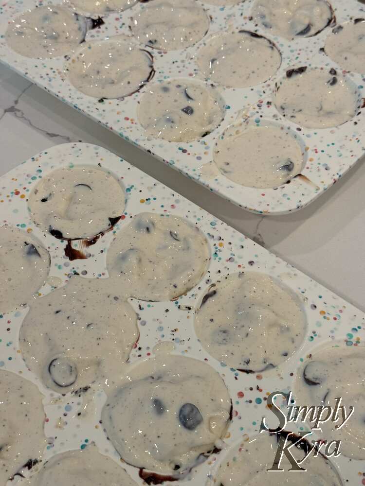 The same silocone trays with while ice cream speckled with brown chunks.