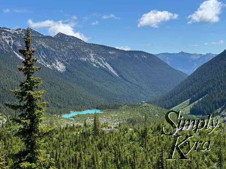 Dab of blue lake against the green trees and hills and blue clouded sky.