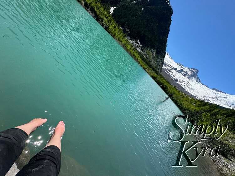 Feet poset above the sparkling water with mountains and glaciers behind.