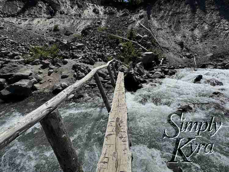 Skinny bridge with single guardrail over the raging river. 