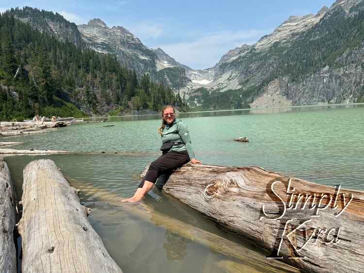 Sitting on a log for a photo framed by the water and mountains.