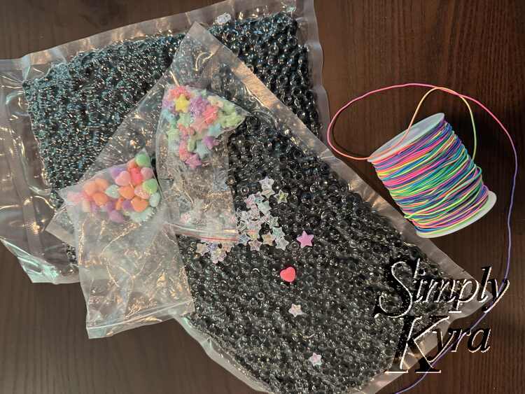 Image shows the vacuumed sealed bags of black, rainbow elastic to the right, and extra stars and hearts on top.