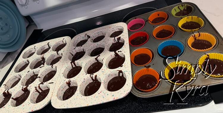 Three cupcake liners partially filled with dark browie mix. The two left ones are speckled silicon while the one on the right is silver with silicon liners.