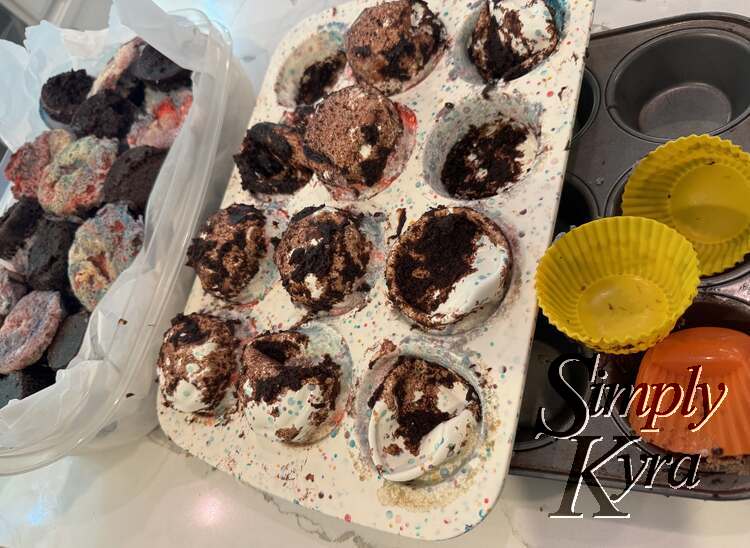 Image shows cupcakes in lined plastic container on left, silicone emptied tray in center, and metal tray with empty liners to the right.