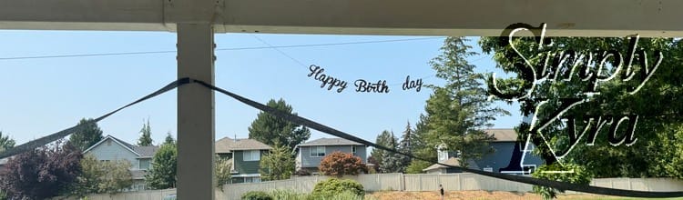 Image shows a "Happy Birth day" banner above some crepe streamer with houses in the background.